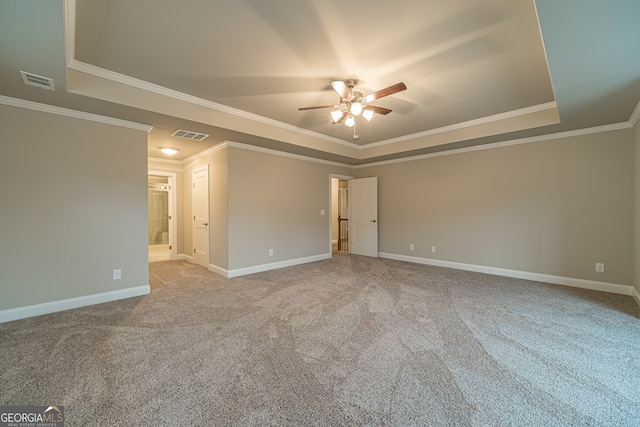 carpeted empty room with ceiling fan, a raised ceiling, and ornamental molding