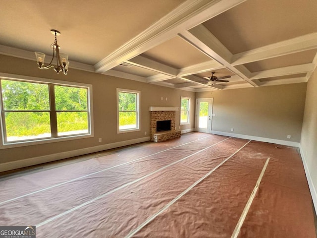 unfurnished living room with a fireplace, ceiling fan with notable chandelier, coffered ceiling, and beam ceiling