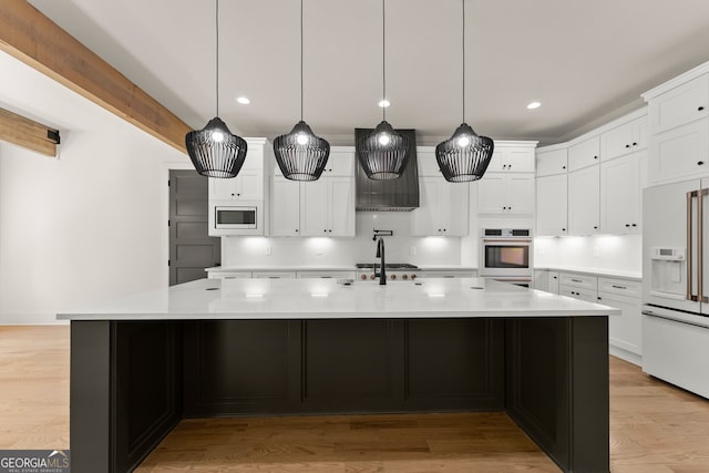 kitchen with a large island with sink, stainless steel appliances, and decorative light fixtures