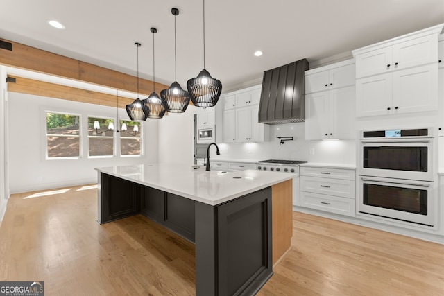 kitchen featuring a center island with sink, light wood-type flooring, appliances with stainless steel finishes, and white cabinets