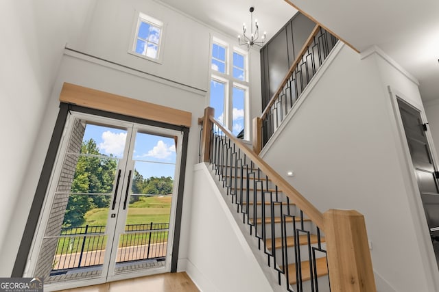 foyer entrance featuring a towering ceiling, a healthy amount of sunlight, light hardwood / wood-style flooring, and a notable chandelier