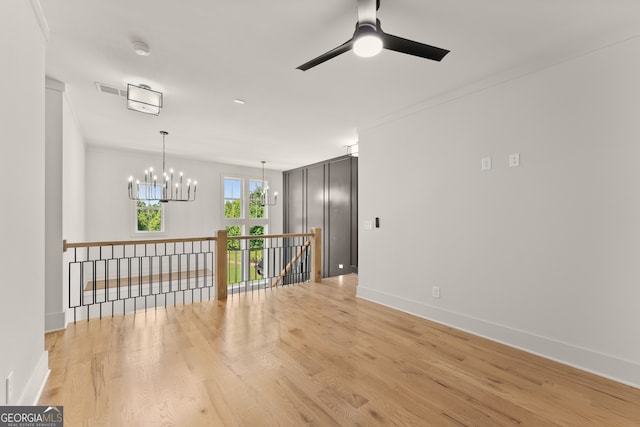 unfurnished room featuring ceiling fan with notable chandelier and light hardwood / wood-style flooring