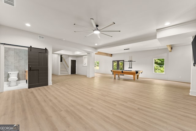 unfurnished living room with billiards, a barn door, ceiling fan, and light hardwood / wood-style floors