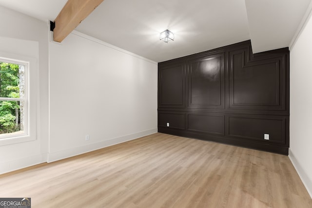 spare room featuring light hardwood / wood-style flooring and beam ceiling