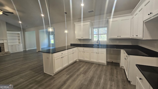 kitchen featuring sink, hanging light fixtures, a brick fireplace, dark hardwood / wood-style flooring, and white cabinetry