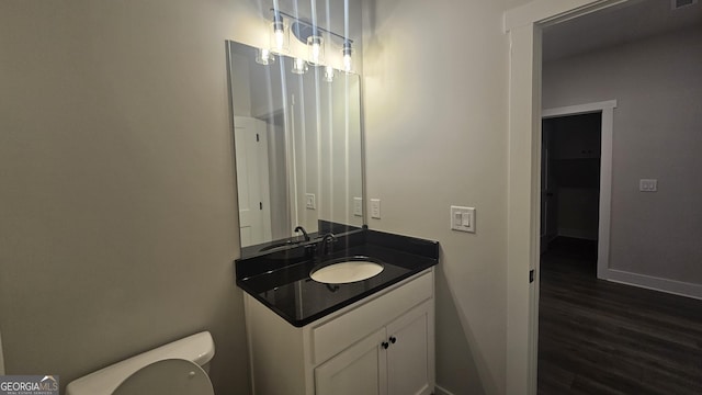 bathroom with wood-type flooring, vanity, and toilet