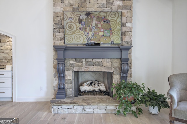 details with hardwood / wood-style floors and a stone fireplace