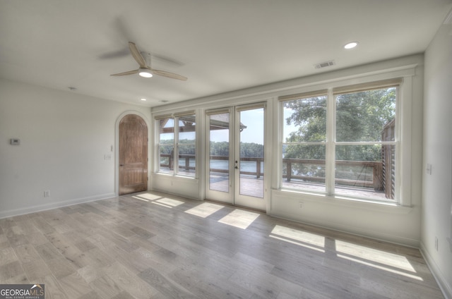 empty room featuring ceiling fan, a water view, and light wood-type flooring