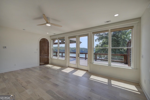 spare room featuring light hardwood / wood-style flooring, ceiling fan, and a water view