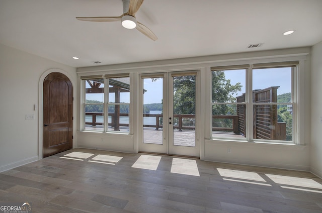 doorway with hardwood / wood-style flooring, a water view, and ceiling fan