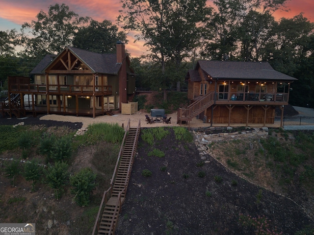 back house at dusk with a patio and a wooden deck