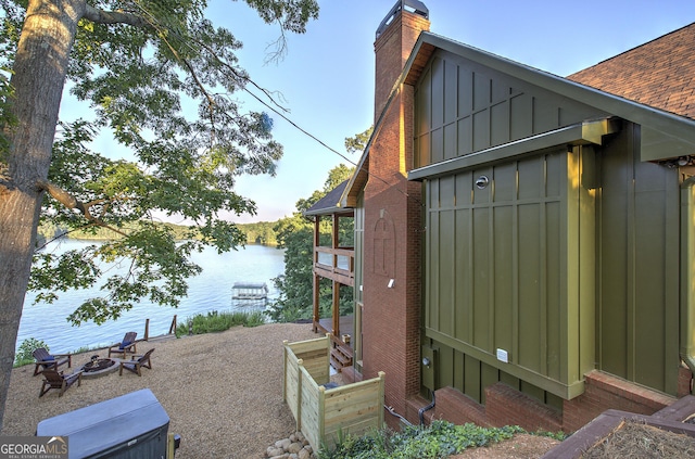 view of side of property with a water view and an outdoor fire pit