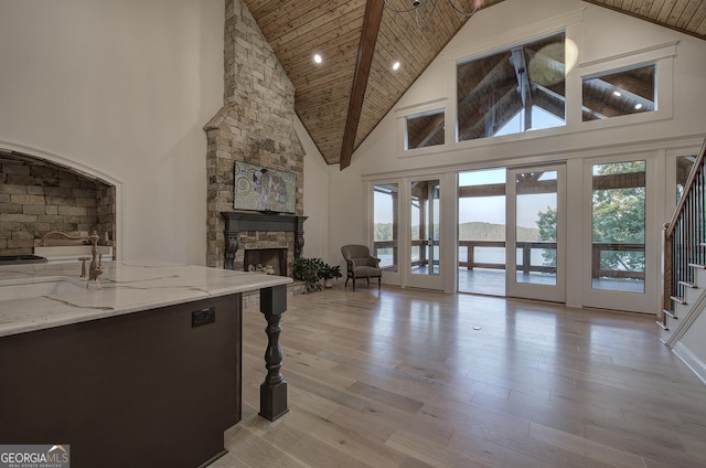 living room featuring high vaulted ceiling, wood ceiling, a fireplace, and light hardwood / wood-style floors