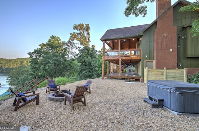 view of yard featuring a deck with water view, a hot tub, and an outdoor fire pit