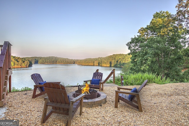 patio terrace at dusk with a fire pit and a water view