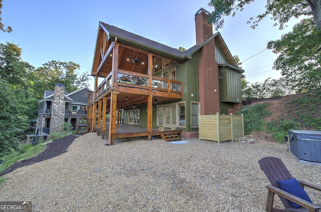 rear view of house with a hot tub, a deck, and ceiling fan