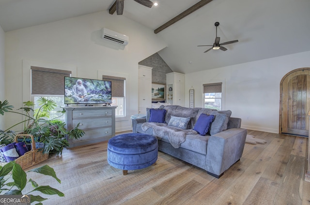 living room with ceiling fan, beam ceiling, high vaulted ceiling, a wall mounted air conditioner, and light hardwood / wood-style floors