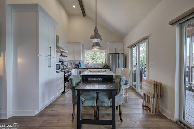 dining room with beamed ceiling, high vaulted ceiling, sink, and light hardwood / wood-style flooring