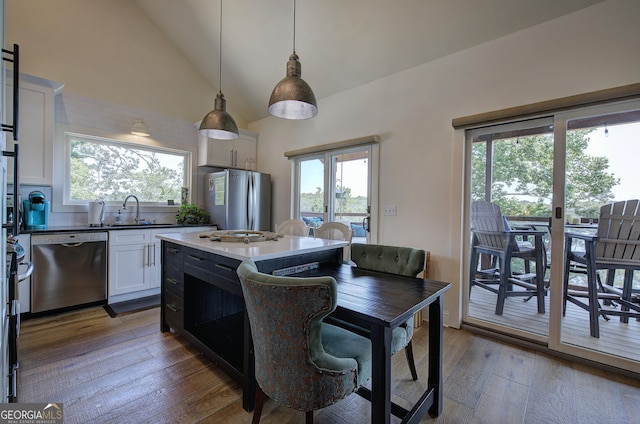 kitchen with appliances with stainless steel finishes, dark hardwood / wood-style floors, pendant lighting, white cabinetry, and sink