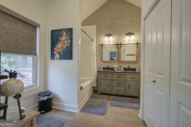 bathroom featuring shower / bath combination with curtain, lofted ceiling, and vanity