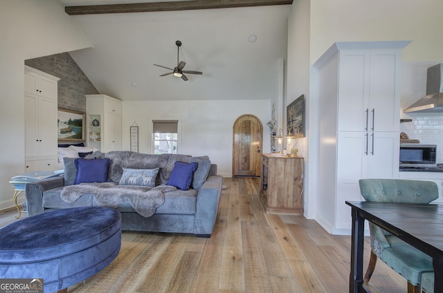 living room with ceiling fan, high vaulted ceiling, beam ceiling, and light hardwood / wood-style floors