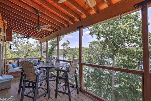 wooden terrace with a water view and ceiling fan