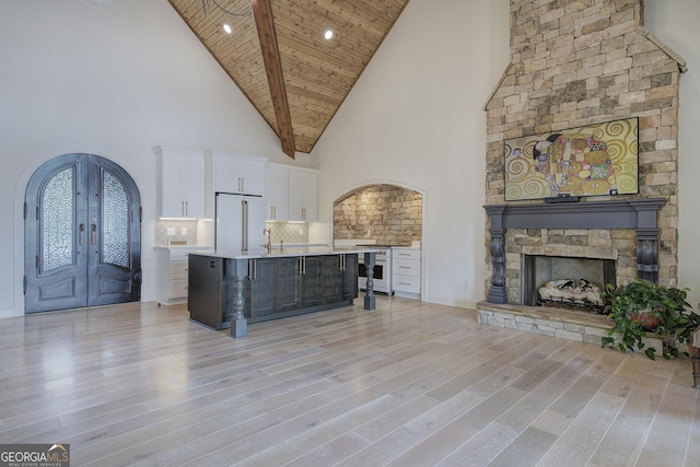 kitchen with a kitchen island with sink, tasteful backsplash, premium appliances, white cabinets, and french doors