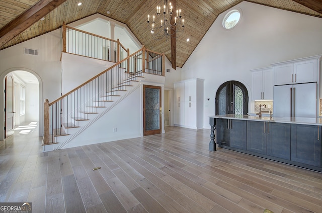 unfurnished living room featuring sink, wood ceiling, an inviting chandelier, high vaulted ceiling, and light hardwood / wood-style floors