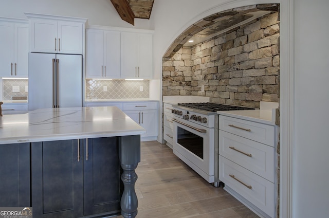 kitchen featuring light hardwood / wood-style flooring, white stove, white cabinetry, backsplash, and built in fridge