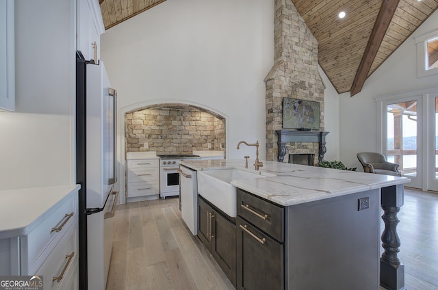 kitchen with sink, white appliances, white cabinetry, a kitchen island with sink, and wooden ceiling