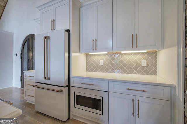 kitchen featuring tasteful backsplash, white cabinetry, high end white fridge, and light hardwood / wood-style flooring