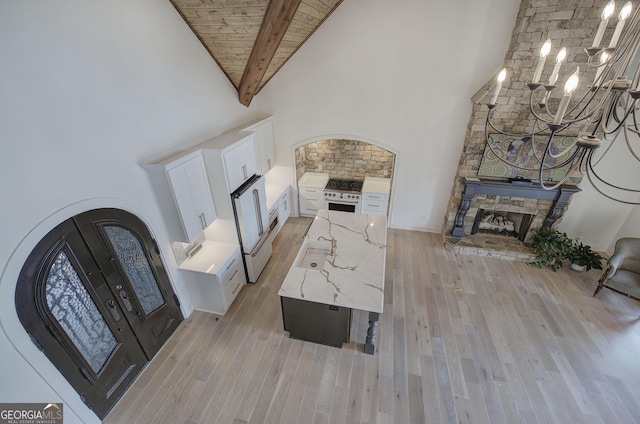 living room with french doors, a stone fireplace, wood ceiling, high vaulted ceiling, and beam ceiling