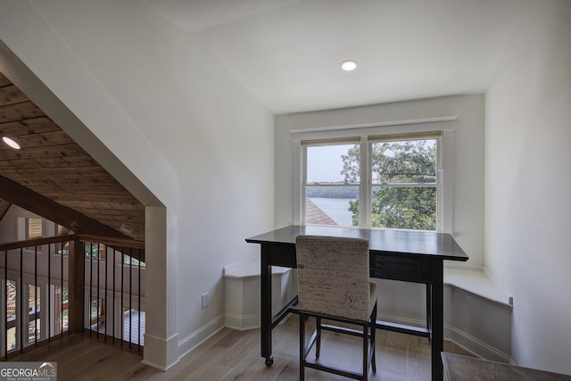 dining area with a water view, lofted ceiling, and hardwood / wood-style floors