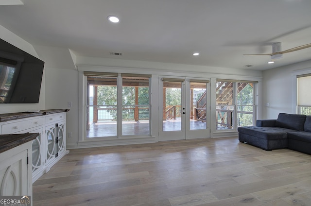 living room with plenty of natural light, light wood-type flooring, and french doors