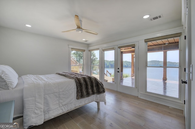 bedroom with wood-type flooring, a water view, access to exterior, and ceiling fan