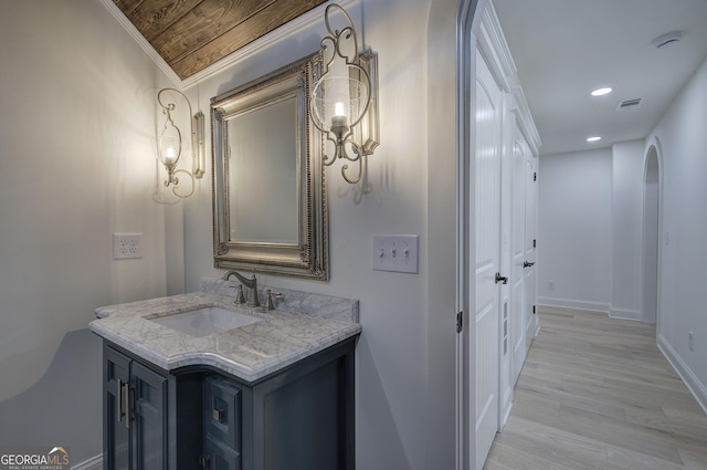 bathroom with hardwood / wood-style flooring, vanity, and crown molding