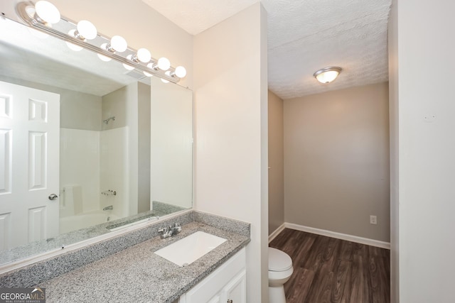 full bathroom with shower / bathtub combination, vanity, a textured ceiling, hardwood / wood-style floors, and toilet