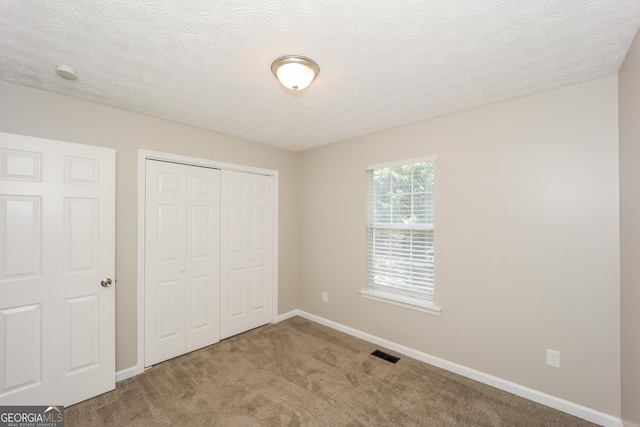 unfurnished bedroom featuring carpet flooring, a textured ceiling, and a closet