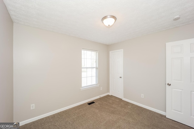 unfurnished room with a textured ceiling and carpet floors