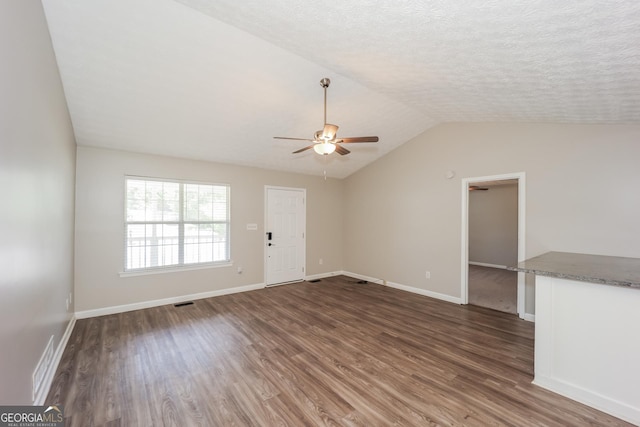 unfurnished living room featuring a textured ceiling, ceiling fan, dark wood-type flooring, and vaulted ceiling