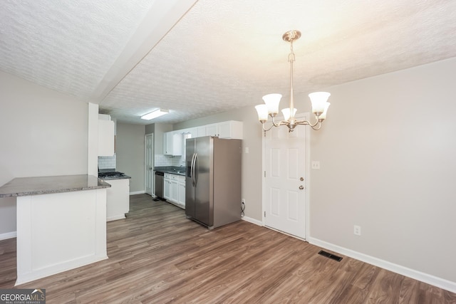 kitchen with white cabinetry, kitchen peninsula, a chandelier, decorative light fixtures, and appliances with stainless steel finishes