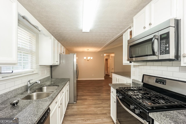 kitchen with dark stone countertops, white cabinets, and appliances with stainless steel finishes