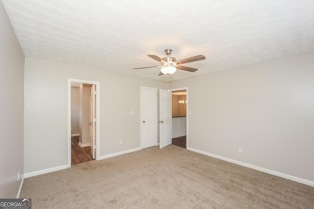 unfurnished bedroom with light carpet, ensuite bath, a textured ceiling, ceiling fan, and a closet