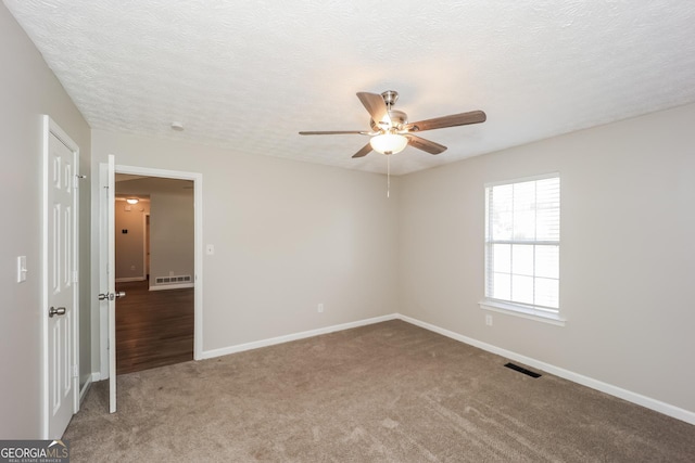 carpeted spare room featuring ceiling fan and a textured ceiling