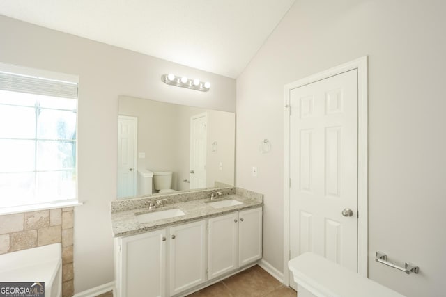 bathroom featuring tile patterned floors, vanity, lofted ceiling, toilet, and a bathing tub