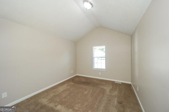 carpeted empty room featuring lofted ceiling and a textured ceiling