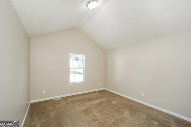 carpeted empty room featuring lofted ceiling