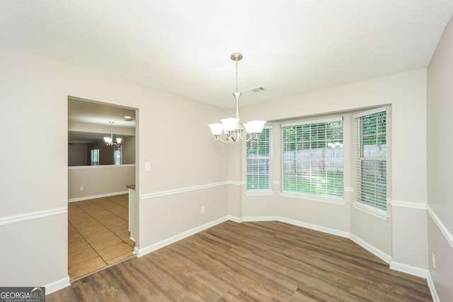 empty room with dark wood-type flooring and a notable chandelier