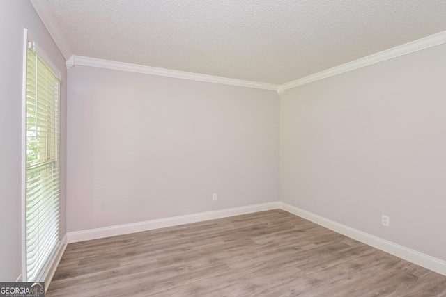 empty room with a textured ceiling, light hardwood / wood-style flooring, and ornamental molding