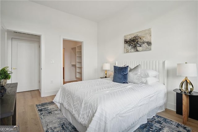 bedroom featuring a walk in closet, light hardwood / wood-style floors, and a closet